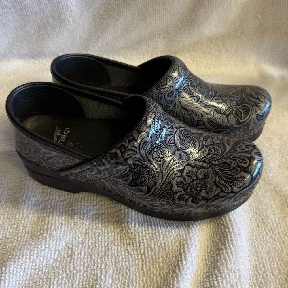 Dansko Professional tooled leather clogs featuring an intricate floral pattern.